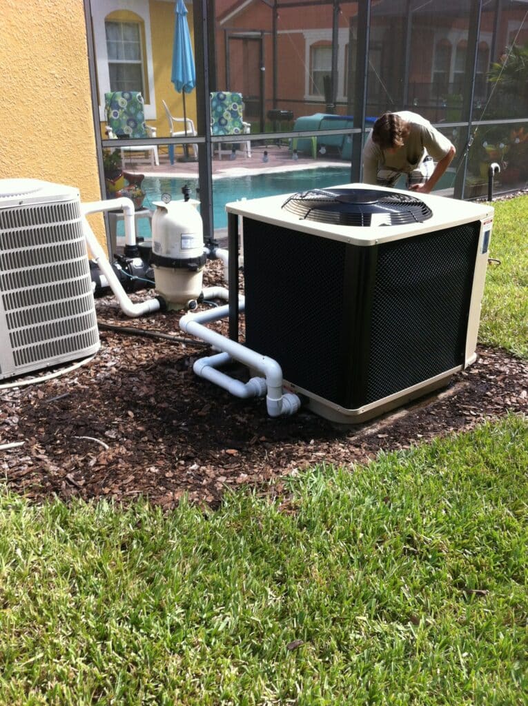 person inspecting pool heater next to pool equipment